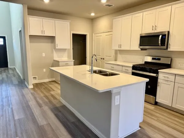 a kitchen with kitchen island a sink refrigerator stove and microwave