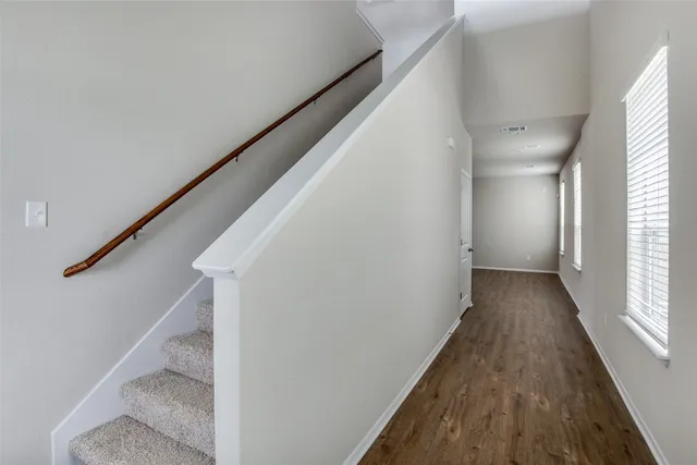 a view of a hallway with wooden floor and staircase