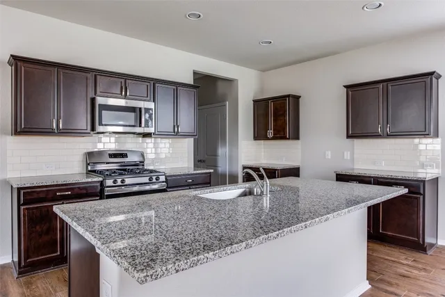 a kitchen with stainless steel appliances granite countertop a sink stove and microwave