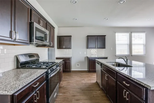 a kitchen with stainless steel appliances granite countertop a sink stove and cabinets