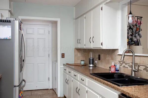 a kitchen with white cabinets and sink