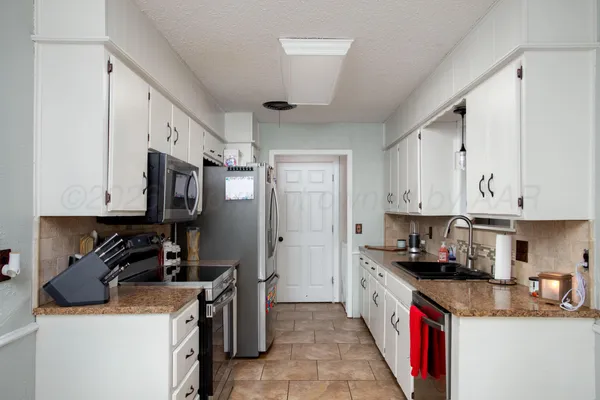 a kitchen with kitchen island granite countertop a sink a stove and refrigerator