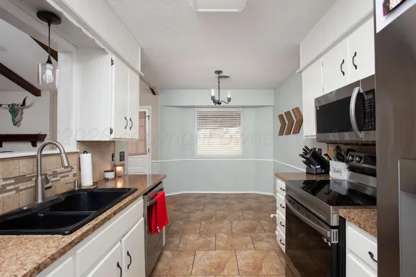 a kitchen with granite countertop a sink stainless steel appliances a counter space and cabinets