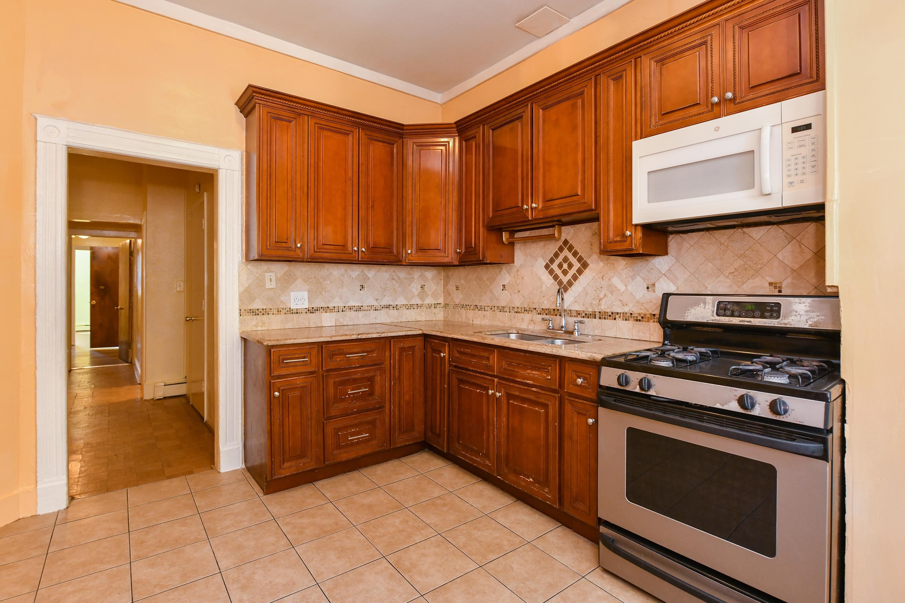 208 4th Street, Unit 1 Passaic, NJ 07055 - Photo 15 of 28 a kitchen with stainless steel appliances granite countertop a stove microwave and cabinets