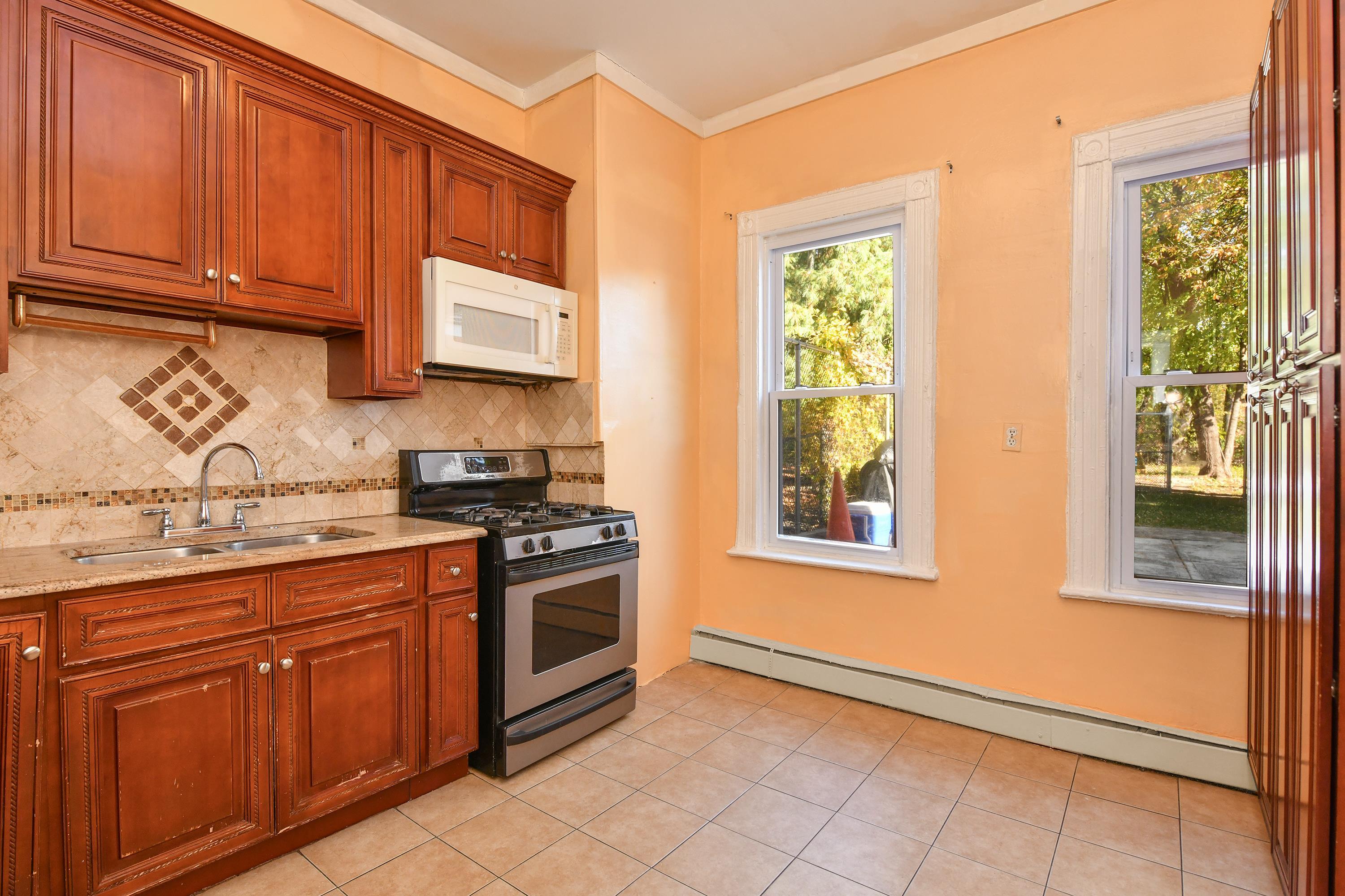 208 4th Street, Unit 1 Passaic, NJ 07055 - Photo 17 of 28 a kitchen with stainless steel appliances granite countertop a stove a sink and a microwave