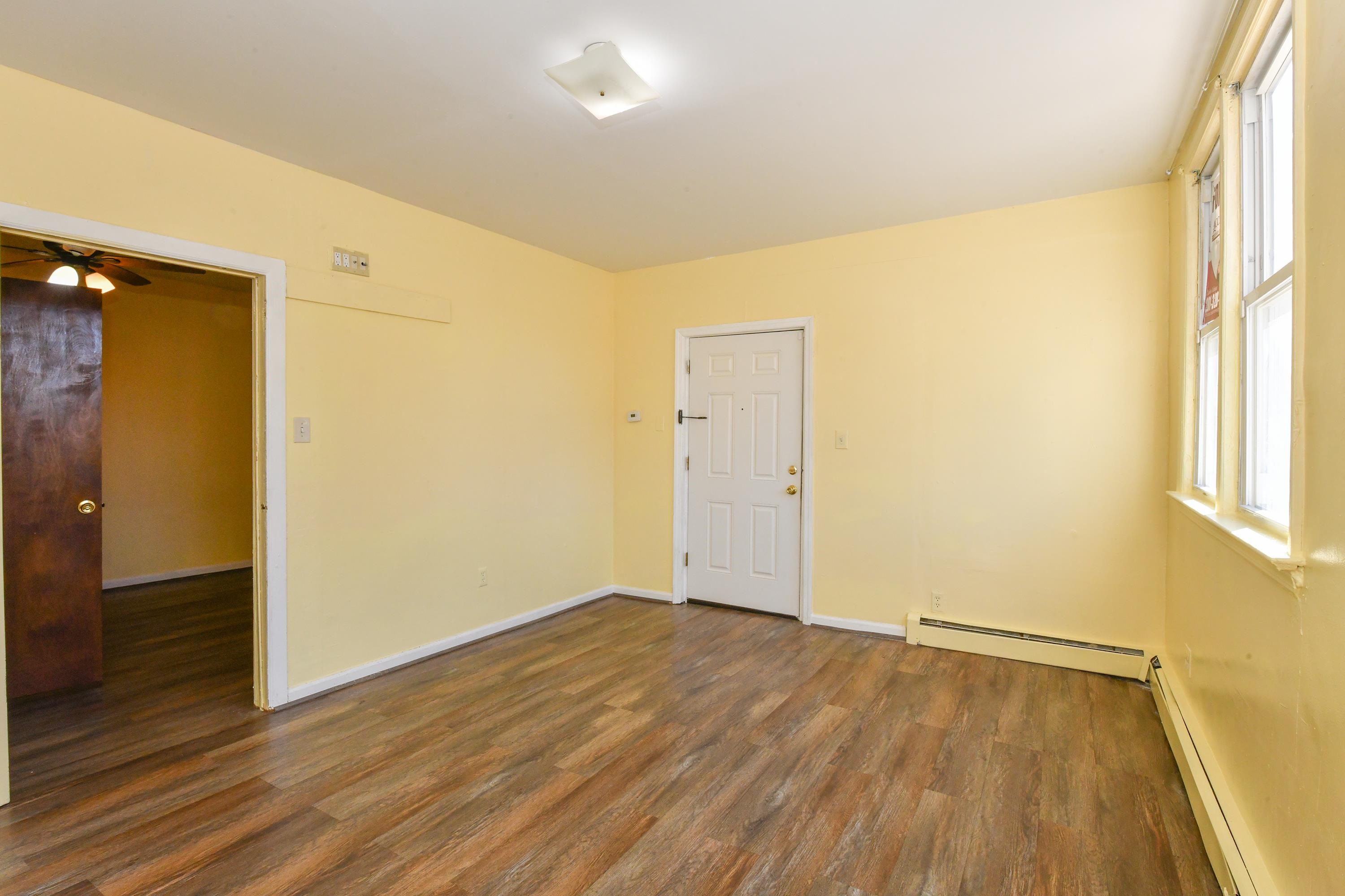 208 4th Street, Unit 1 Passaic, NJ 07055 - Photo 5 of 28 an empty room with wooden floor and windows