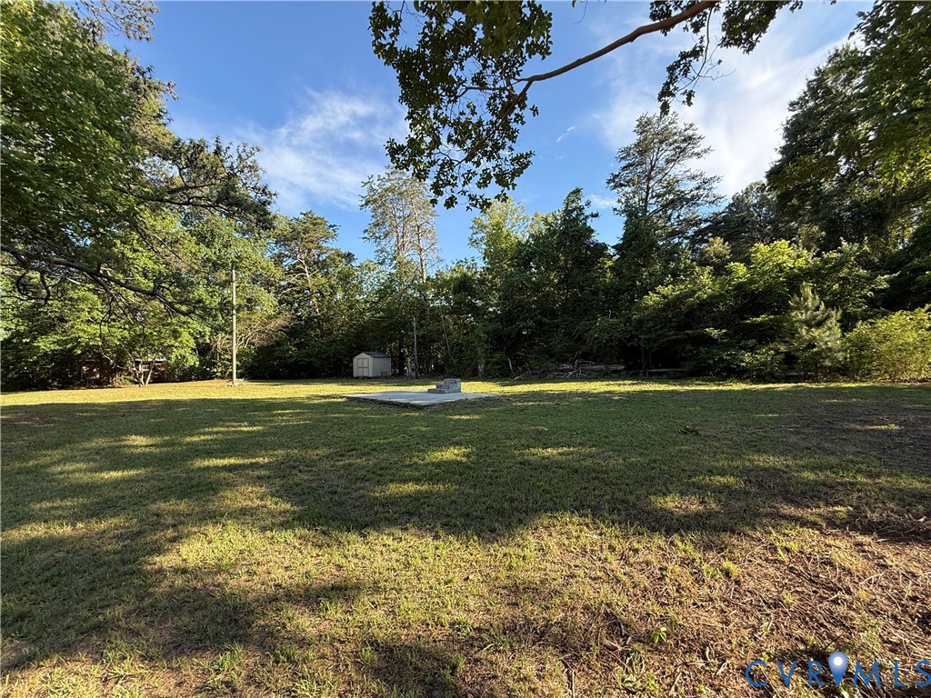 Expansive grassy lot featuring mature trees, a con