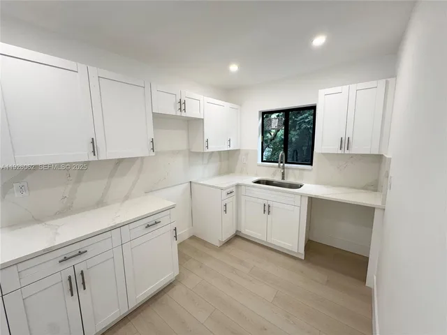 a kitchen with white cabinets and sink