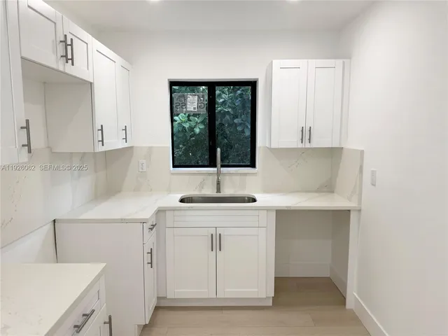 a kitchen with granite countertop white cabinets and white appliances