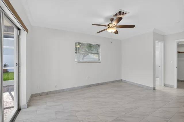 an empty room with windows and fan