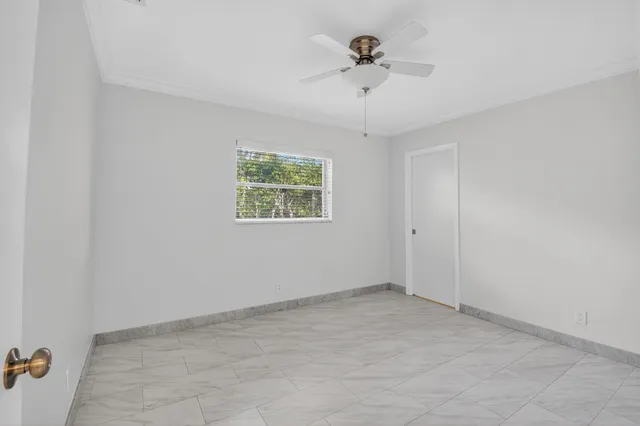 an empty room with a chandelier fan and windows