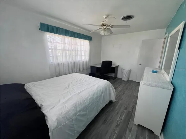 a bedroom with a bed and a large mirror next to a window