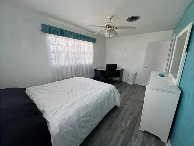 a bedroom with a bed and a large mirror next to a window