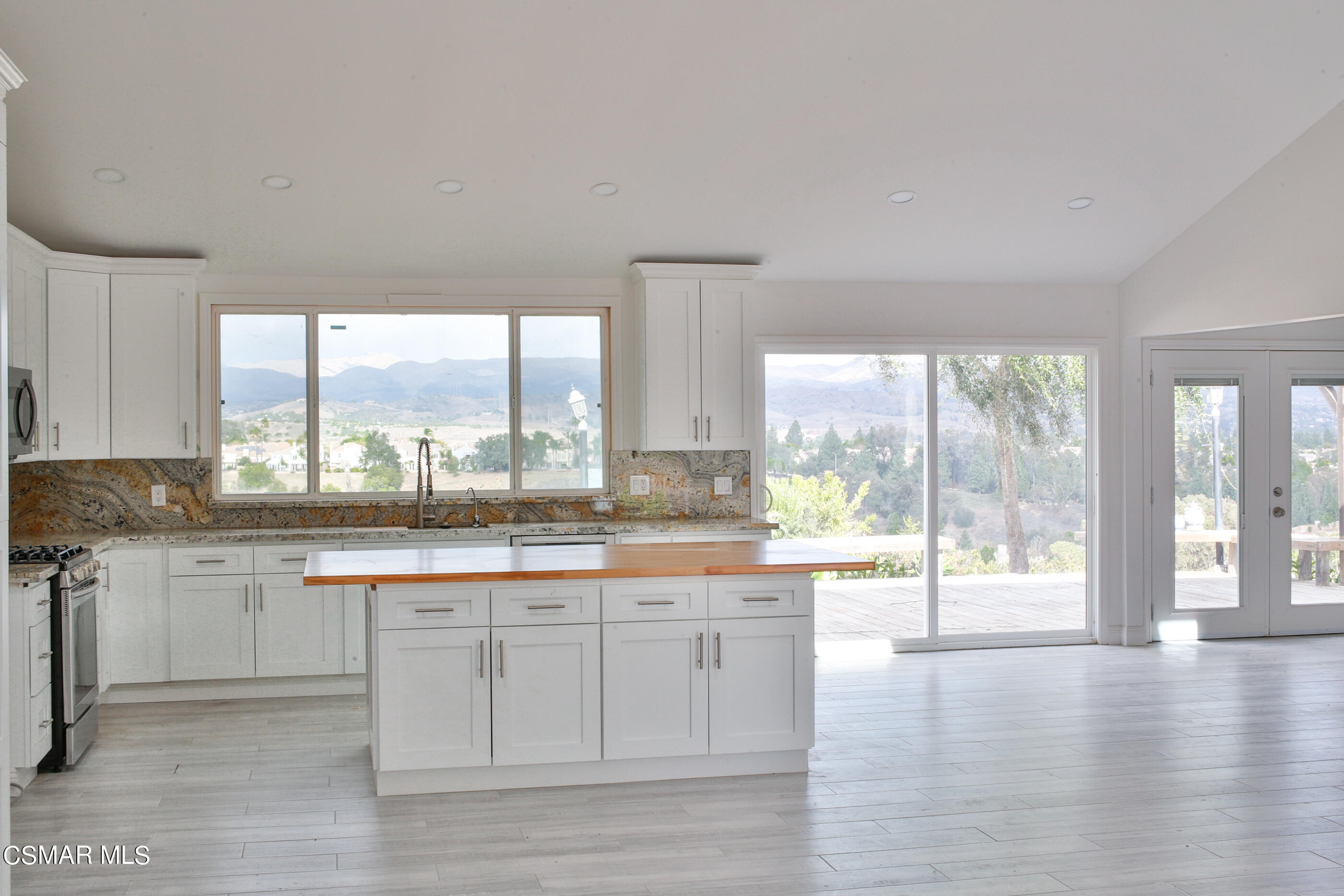 3836 Dalaway Drive Moorpark, CA 93021 - Photo 15 of 29 a large kitchen with granite countertop a stove a sink and white cabinets with wooden floor next to windows