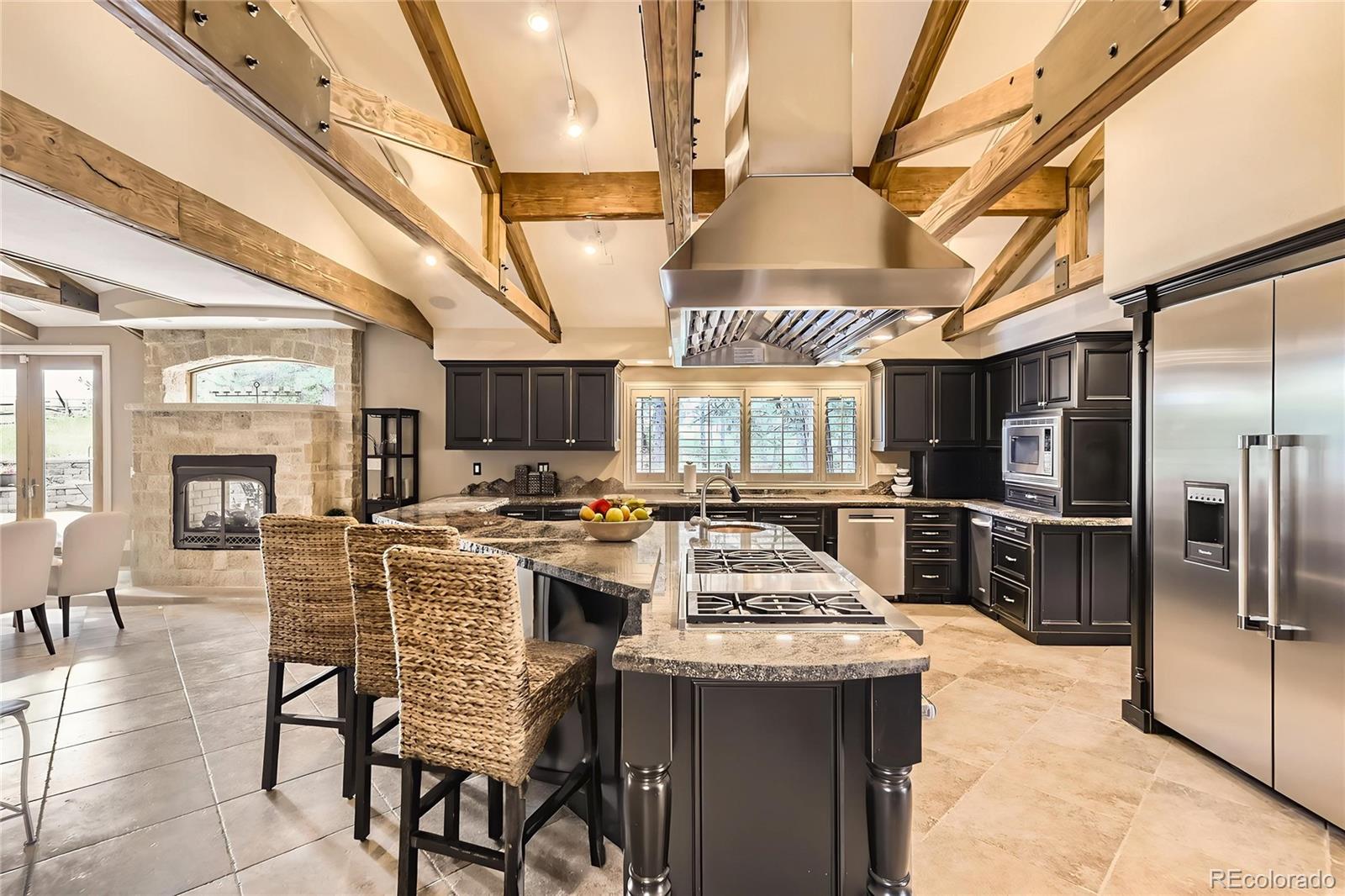 11274 East Manitou Road Franktown, CO 80116 - Photo 15 of 46 a kitchen with stainless steel appliances kitchen island granite countertop a table chairs and a refrigerator