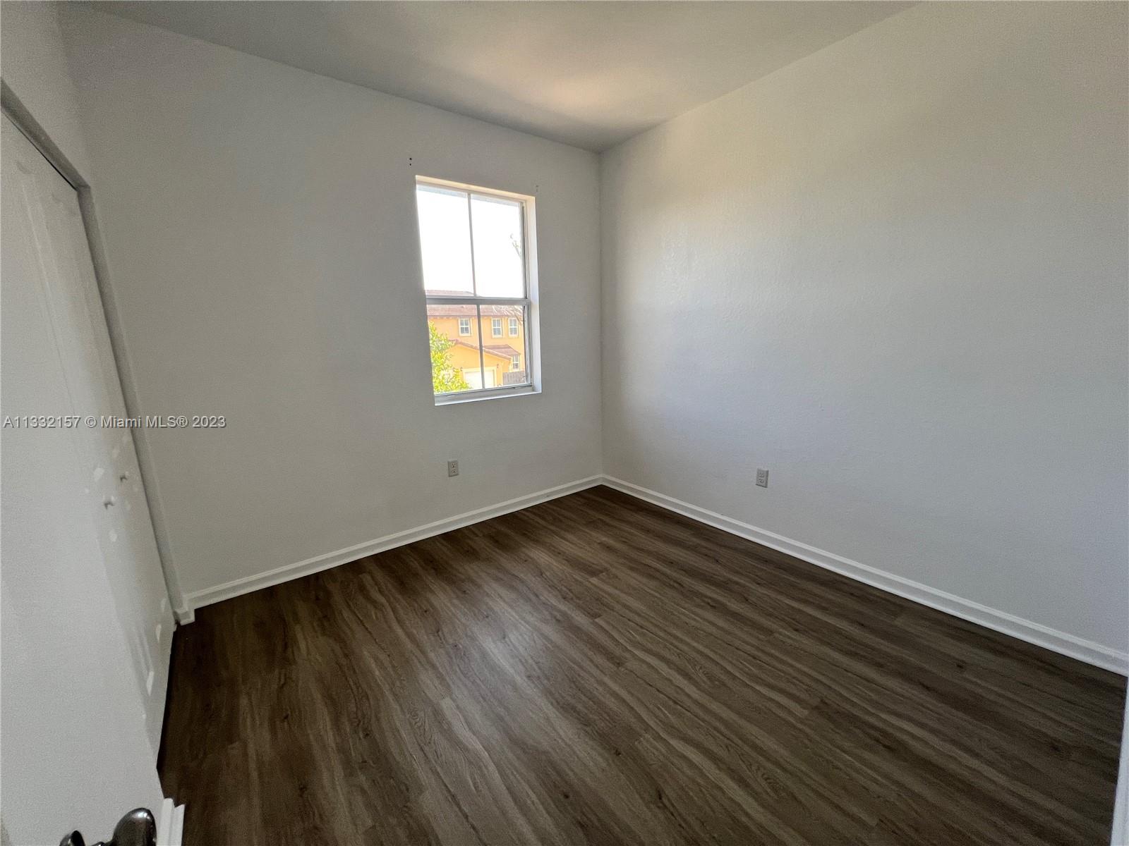 24257 Southwest 117th Avenue Homestead, FL 33032 - Photo 26 of 27 an empty room with wooden floor and windows
