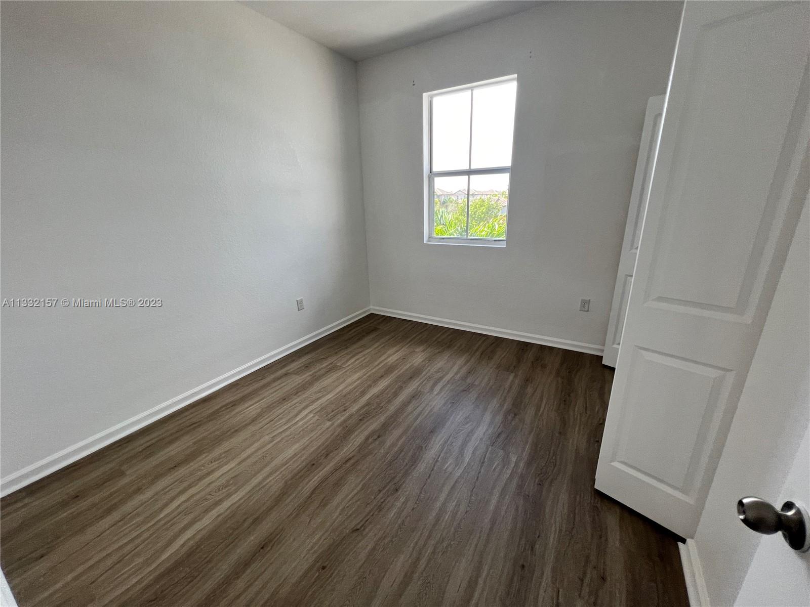 24257 Southwest 117th Avenue Homestead, FL 33032 - Photo 27 of 27 an empty room with wooden floor and windows