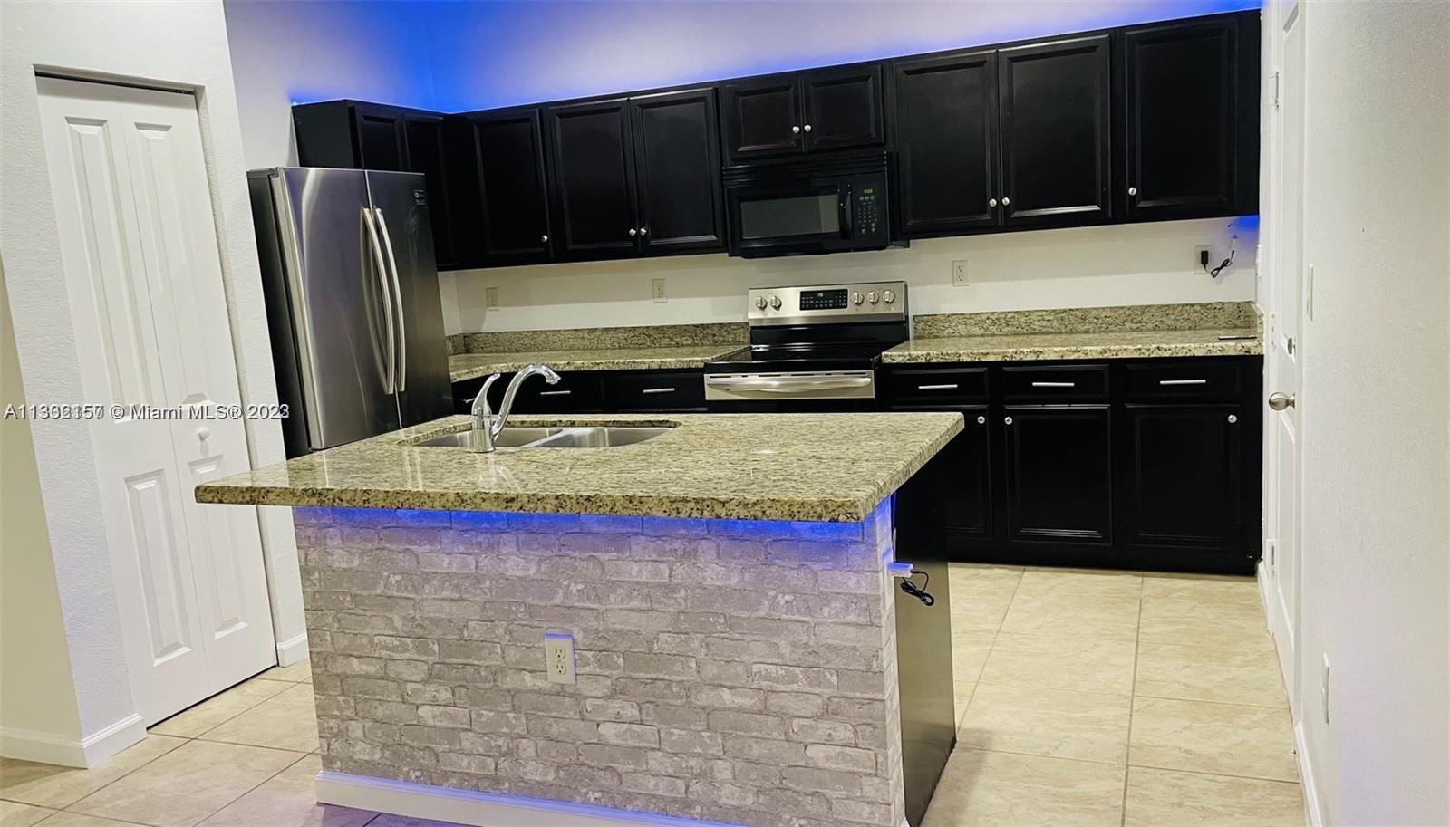 24257 Southwest 117th Avenue Homestead, FL 33032 - Photo 8 of 27 a kitchen with stainless steel appliances granite countertop a stove a refrigerator and a microwave