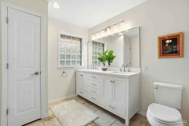 a bathroom with a sink a mirror a toilet and window