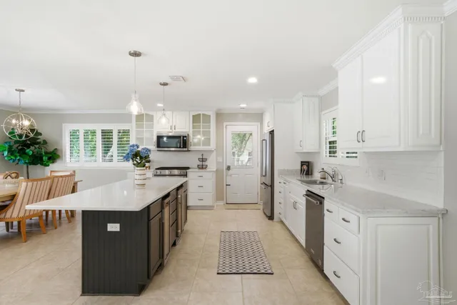 a large kitchen with stainless steel appliances lots of white cabinets and a chandelier
