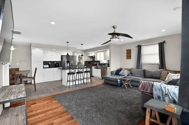 a living room with furniture kitchen view and a wooden floor