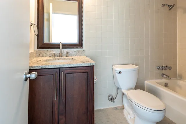 a bathroom with a granite countertop toilet a sink and a mirror