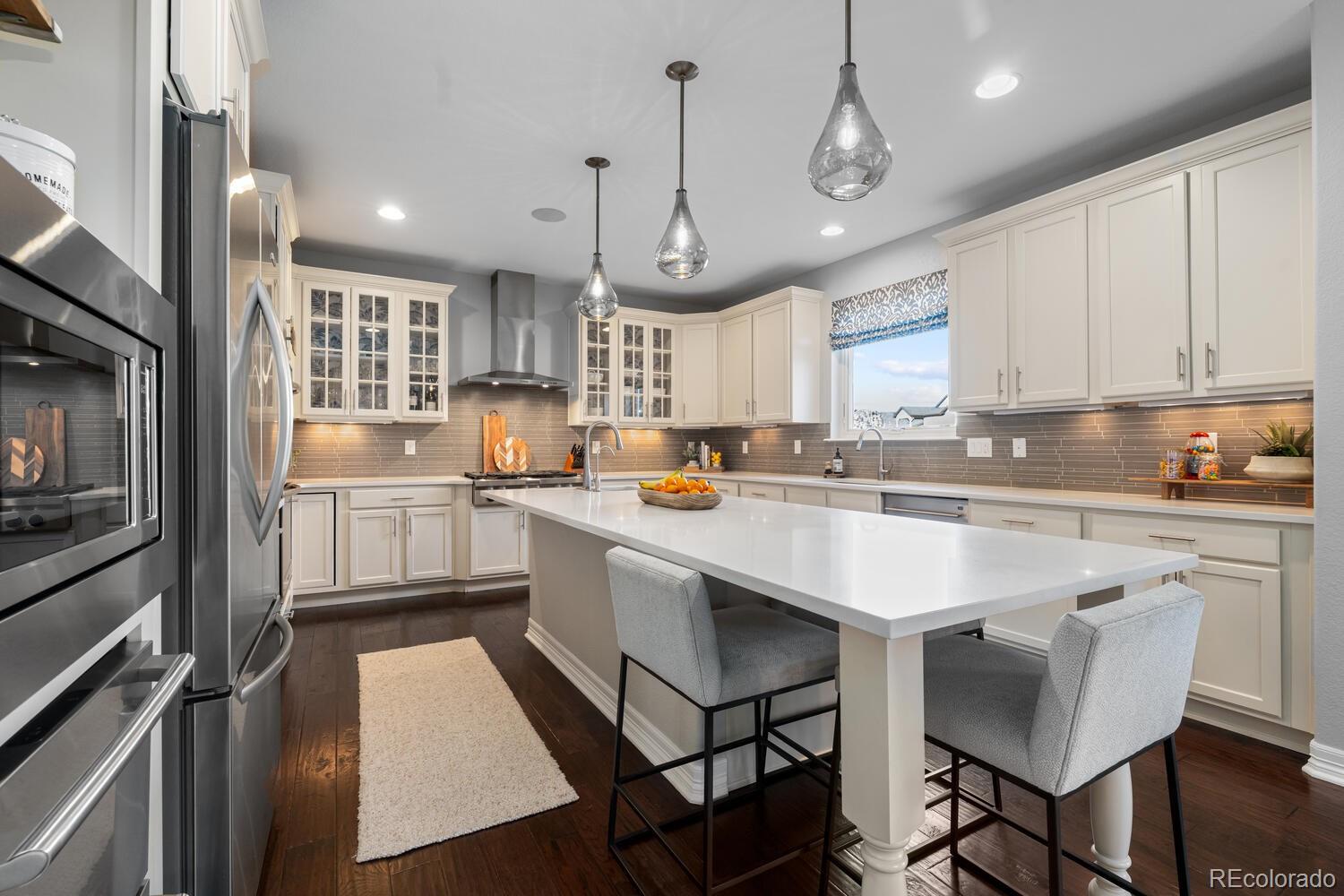 10800 Sundial Rim Road Highlands Ranch, CO 80126 - Photo 12 of 48 a kitchen with stainless steel appliances granite countertop a refrigerator a sink dishwasher a stove and white cabinets with wooden floor