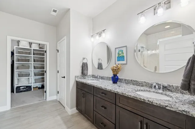 a bathroom with a granite countertop double vanity sink and a mirror