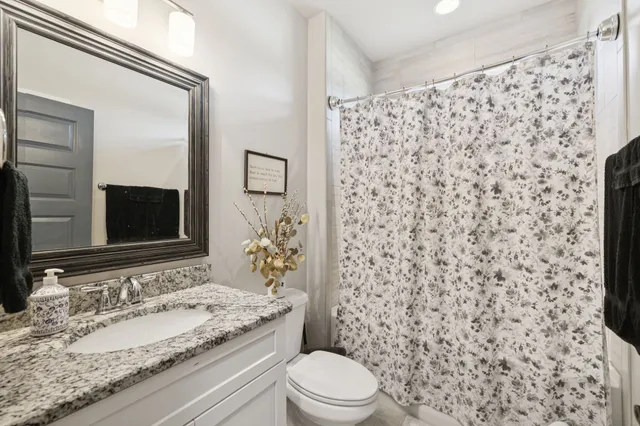 a bathroom with a granite countertop sink toilet and shower