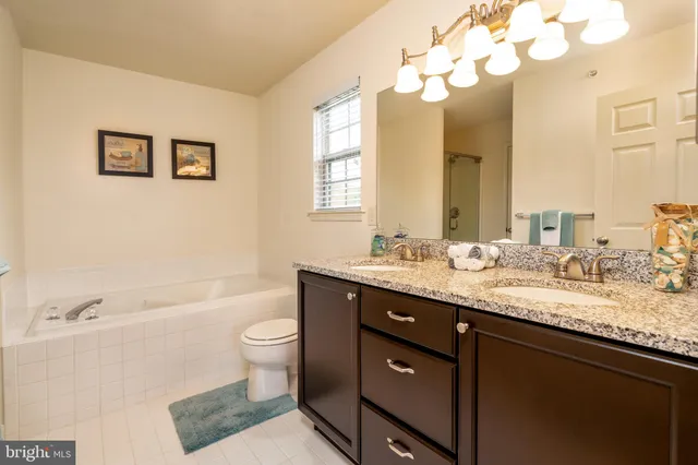 a bathroom with a granite countertop sink mirror vanity and toilet