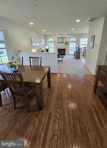 a living room with stainless steel appliances furniture wooden floor and a kitchen view