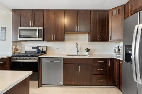 a kitchen with stainless steel appliances granite countertop a refrigerator and a stove top oven