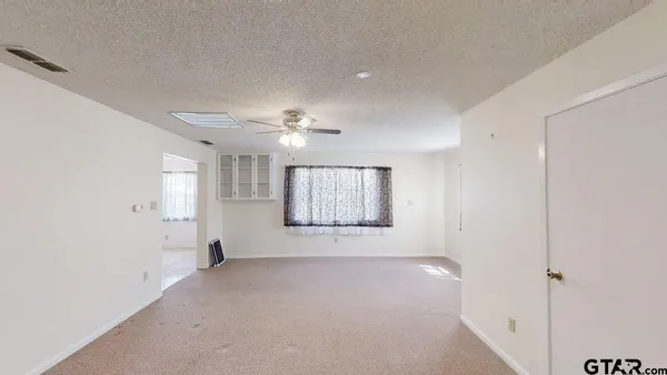 an empty room with windows and fan