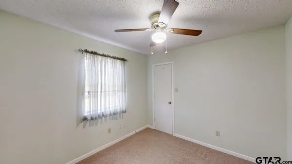 an empty room with windows and fan
