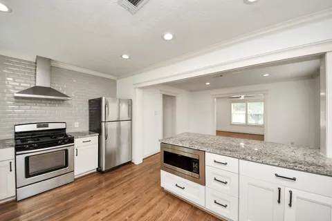 a kitchen with granite countertop a sink and wooden floor
