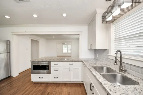 a kitchen with granite countertop sink window and cabinets