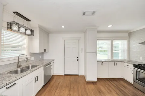 a kitchen with stainless steel appliances granite countertop a sink cabinets and wooden floor