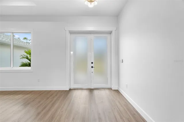an empty room with wooden floor and windows