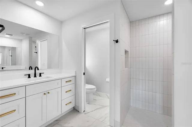 a spacious bathroom with a double vanity sink a toilet and a shower