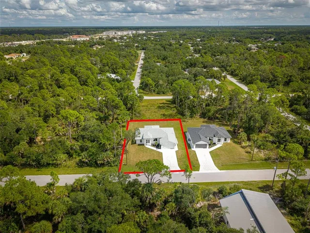 an aerial view of residential houses with outdoor space and trees