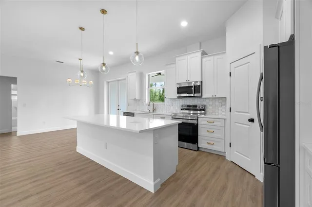 a large kitchen with stainless steel appliances a large counter top a stove a refrigerator and a view of living room