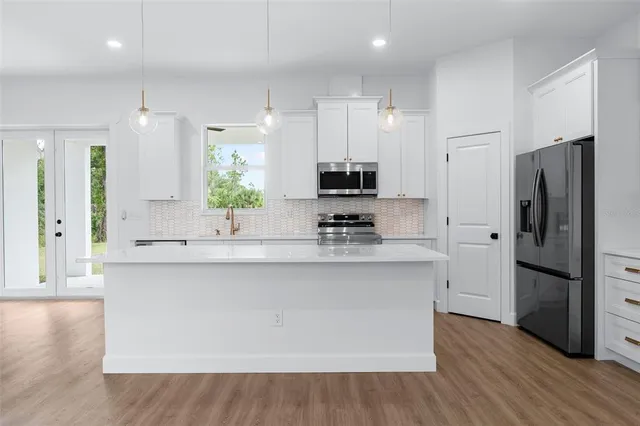 a large kitchen with stainless steel appliances a large counter top a stove a refrigerator and a sink