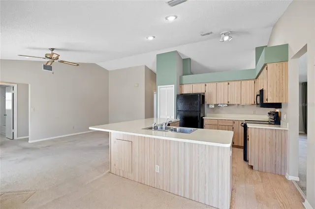 a room with stainless steel appliances kitchen island a sink a stove a refrigerator and cabinets
