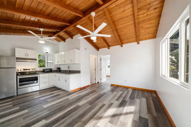 a kitchen with a sink dishwasher a stove and white cabinets with wooden floor
