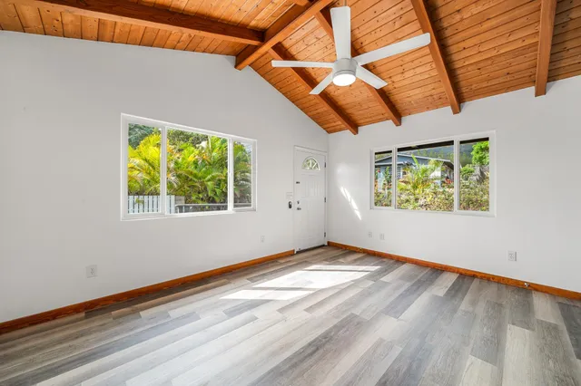 a view of an empty room with a window and wooden floor