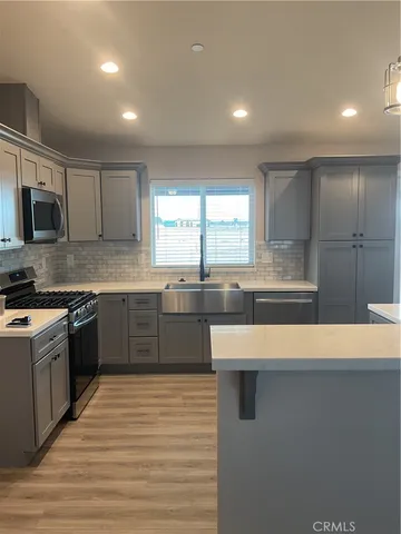 a large kitchen with stainless steel appliances granite countertop a stove a sink and a microwave