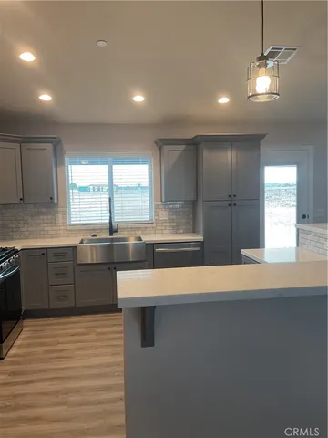 a large kitchen with stainless steel appliances a large counter top a stove a chimney a sink and a refrigerator