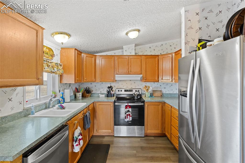 20480 Drennan Road Colorado Springs, CO 80928 - Photo 12 of 47 a kitchen with stainless steel appliances granite countertop a refrigerator a sink dishwasher a stove and white countertops with wooden floor