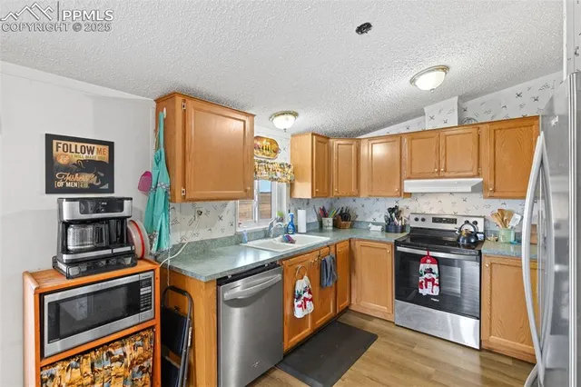 a kitchen with stainless steel appliances granite countertop a stove a sink and a refrigerator