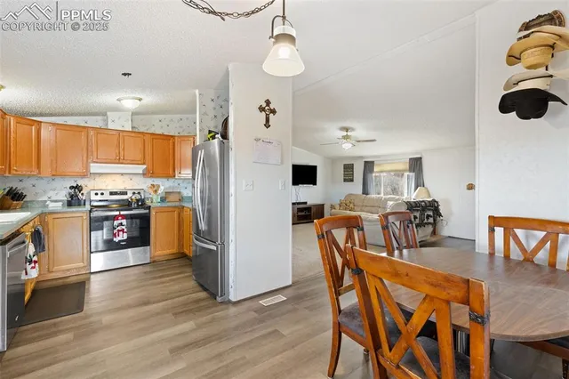 a kitchen with stainless steel appliances granite countertop a refrigerator a stove top oven a sink dishwasher and white cabinets with wooden floor